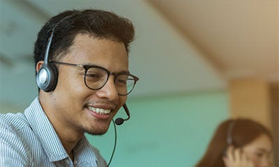 man smiling with a headset on in a office