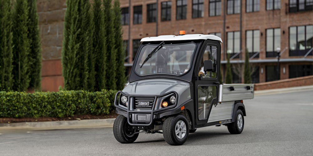 A Club Car Carryall vehicle drives down a road.