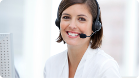 Smiling woman wearing a headset, sitting at a desk with a computer.
