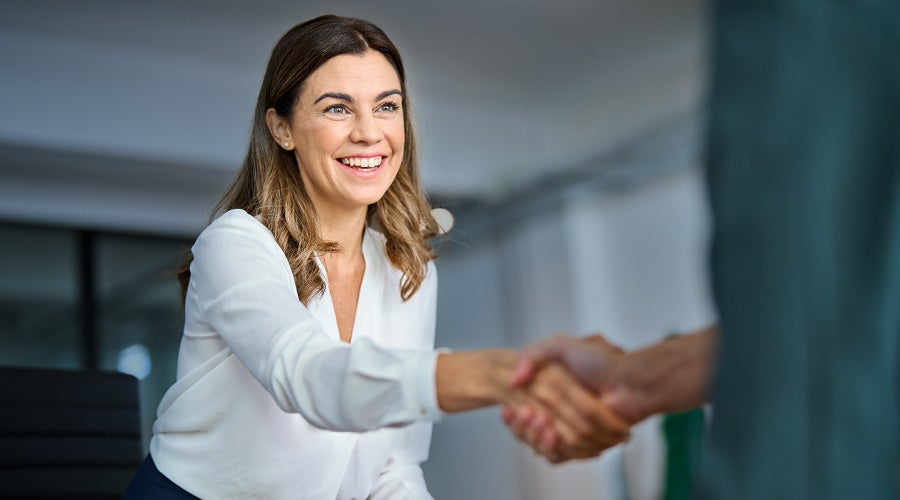 Professional woman smiling and shaking hands in a business setting, representing a successful partnership with Chatsworth Products.