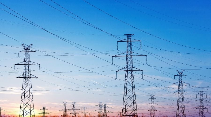 High-voltage transmission towers and power lines stretching across the landscape, illustrating grid capacity and electrical infrastructure constraints.