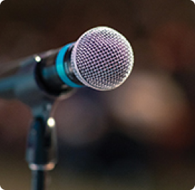 Close-up of a microphone on a stand, with a blurred background.