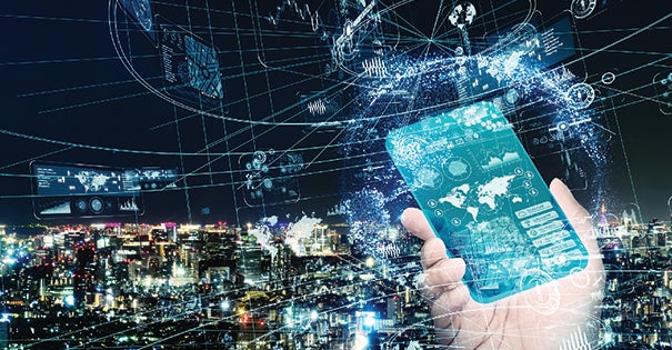 Hand holding a smartphone displaying digital data over a city skyline at night.