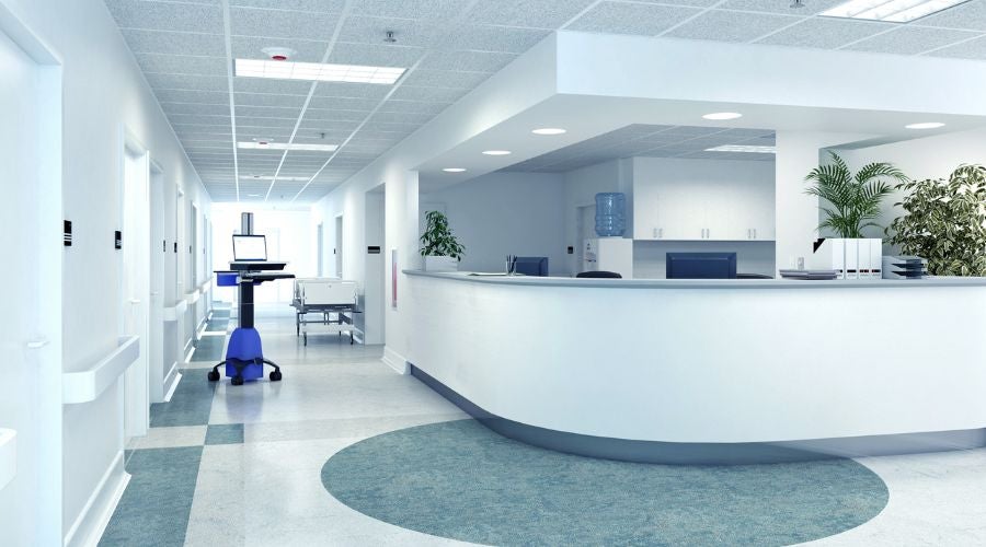 Brightly lit hospital reception area with a curved desk and medical equipment.