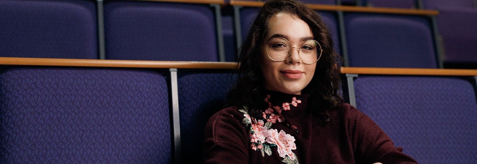 Student sitting on lecture hall seat smiling