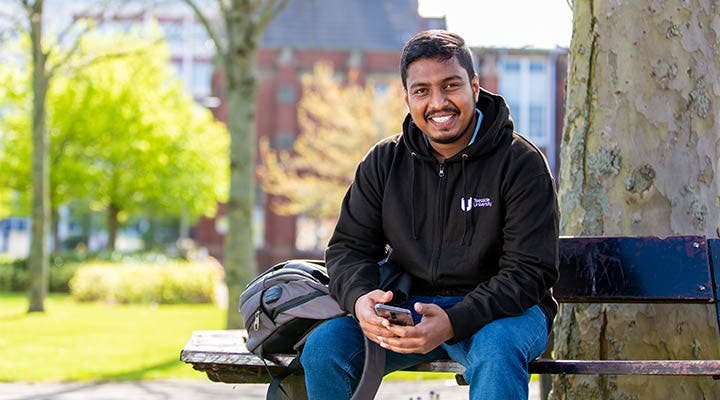 Student sitting on bench outside campus