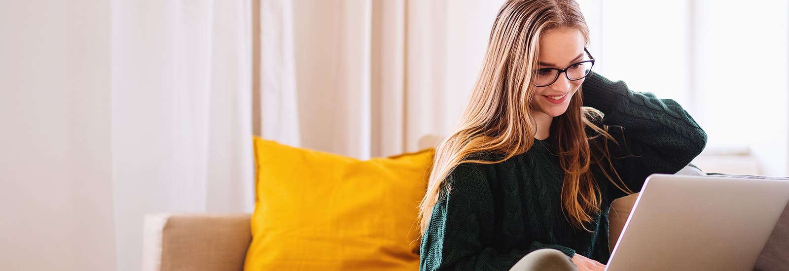 A student sitting on a sofa using a laptop