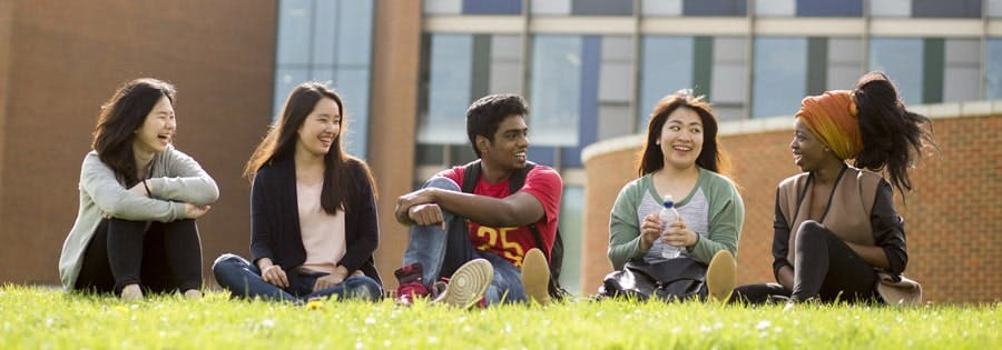 Students sitting on green outside campus