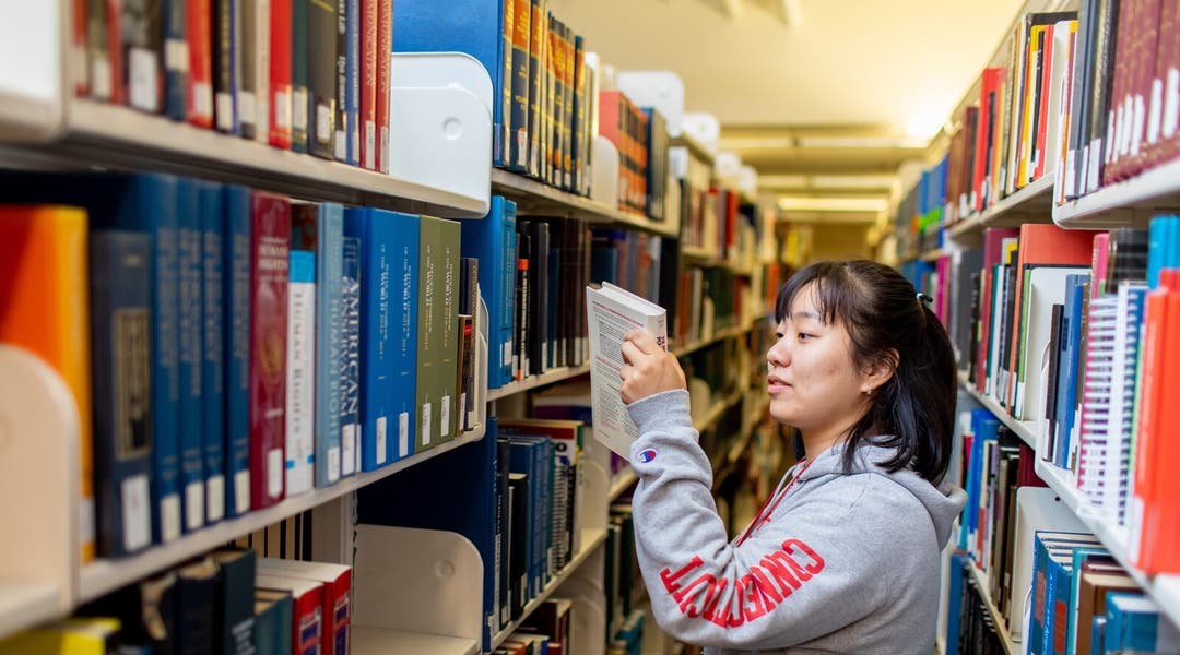 A student in the library holding a book.