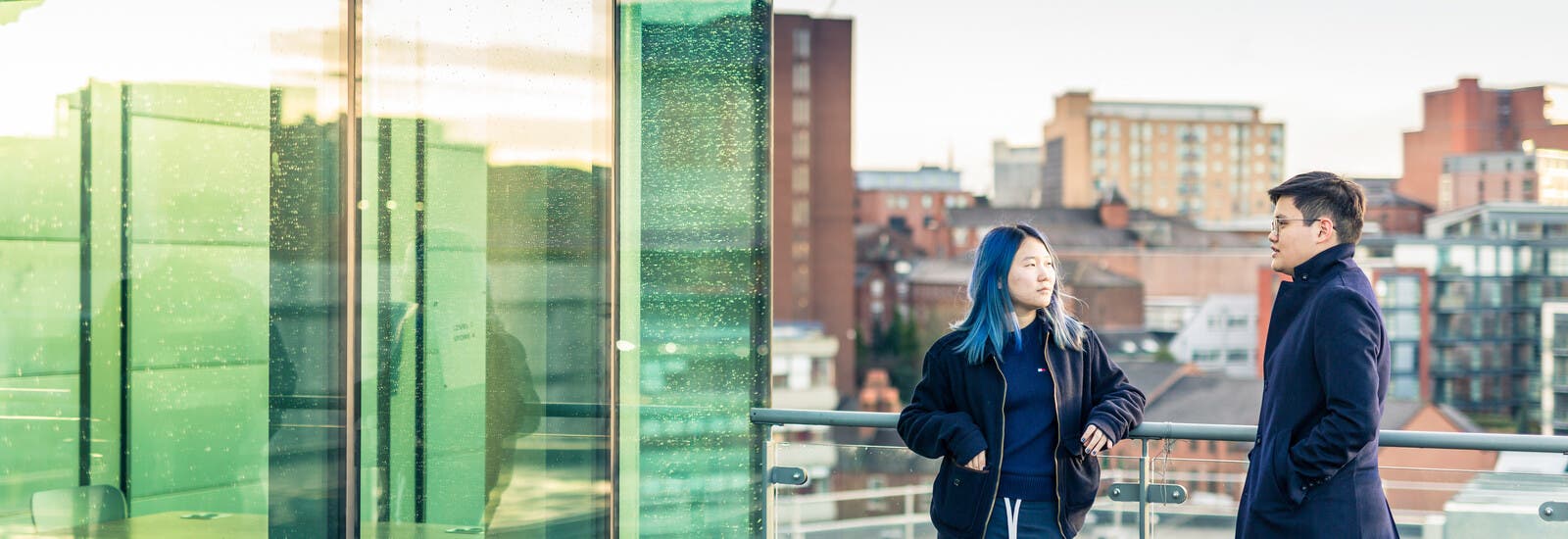Two students standing outside on a balcony on campus