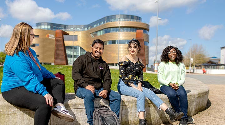 Students sitting on wall outside Teesside University campus