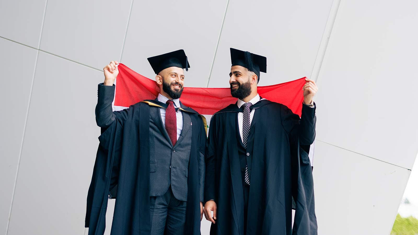 Graduates smiling and holding up a flag