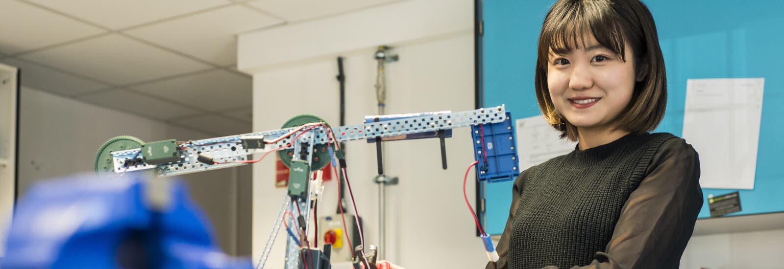 Engineering student smiling at camera while holding model