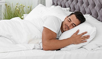 A man sleeps in bed after using a Sunlighten infrared sauna.