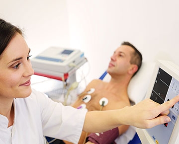 A doctor monitors the vital signs of a patient fitted with electrodes and a heart monitor.