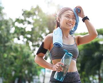 Woman wiping sweat off her face with a towel after exercising