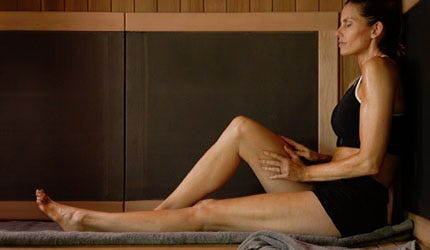 woman sits in infrared sauna relaxing