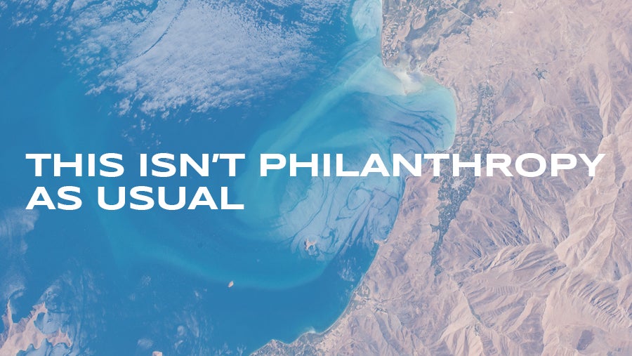 An overhead view or mountains and ocean with the words This isn't philanthropy as usual overlaid