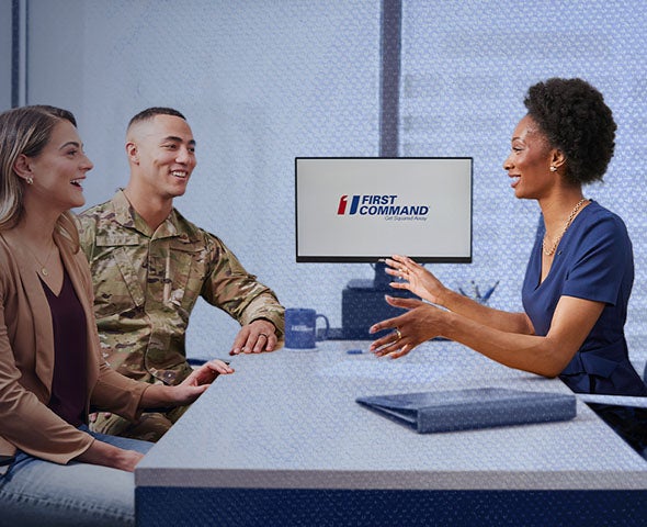financial advisor consulting with a couple at a desk with a first command logo on the monitor in the background