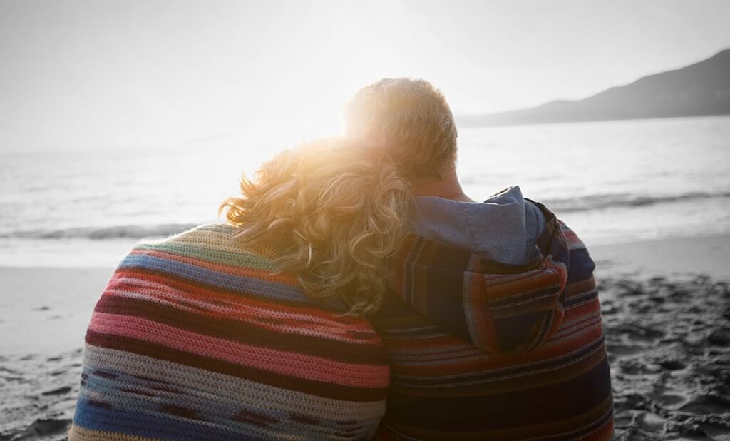 A couple embracing on the beach looking out into a sunset