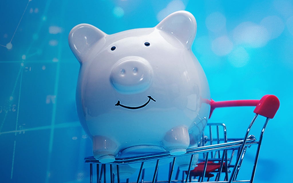 Piggy bank riding in a shopping cart with a blue background.