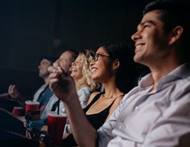 Photo of a row of patrons in a movie theater with popcorn