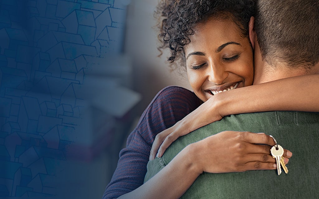 Military member hugging her spouse with new home keys in her hand.