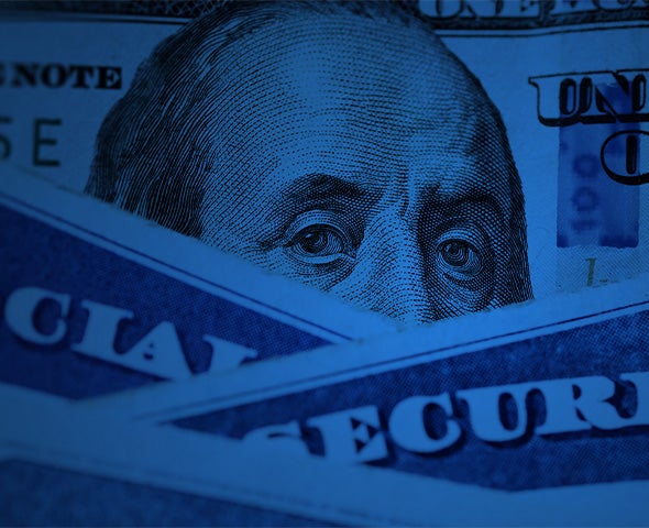 Close-up of Benjamin Franklin’s face on a U.S. $100 bill, partially covered by Social Security cards in blue lighting.