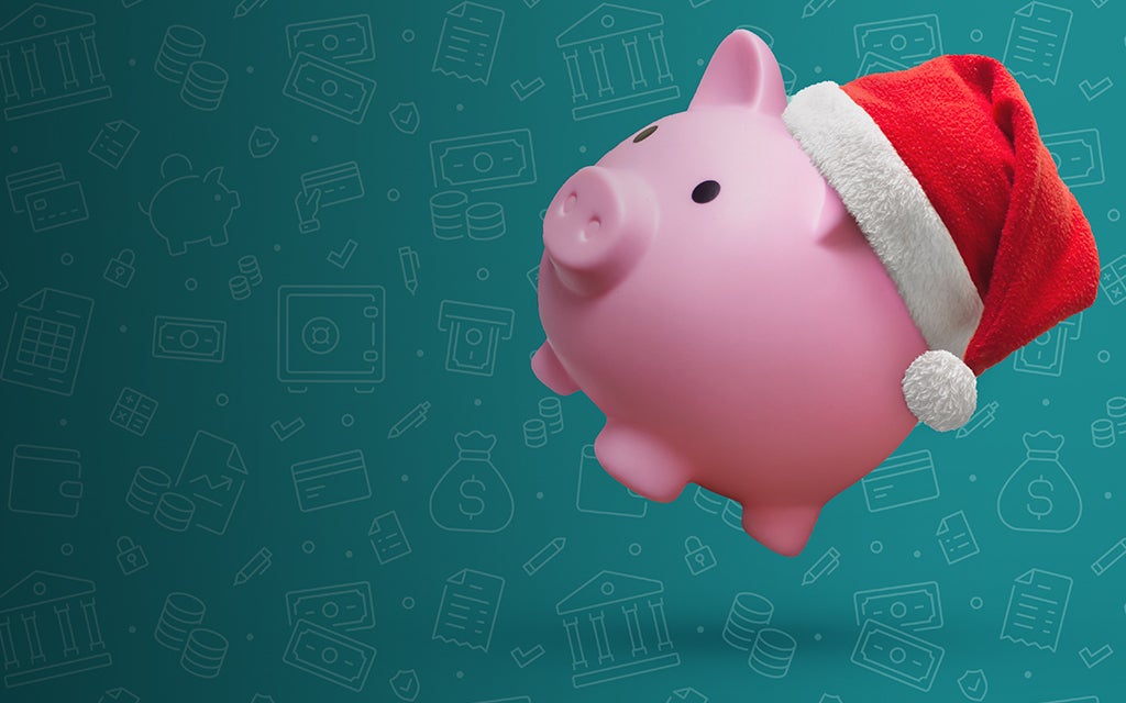 Pink piggy bank wearing a Santa hate on a green background with money iconography.