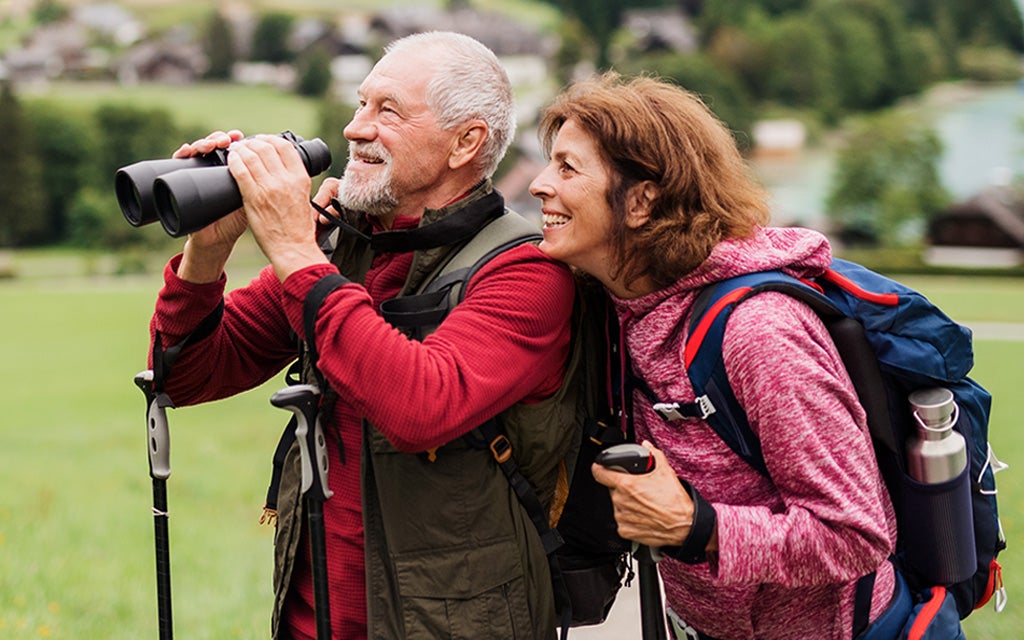 Older couple enjoying a view while using binoculars.