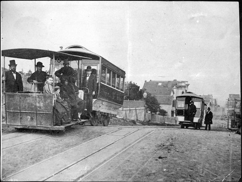 Clay Street Hill R.R. grip car no. 7 with trailer, at the summit of Nob Hill, San Francisco, with another cable car, unidentifiable, on the way down; the second gentleman from the left has his hand on the grip; photograph, 1873, San Francisco Municipal Transportation Agency archives (sfmta.com)