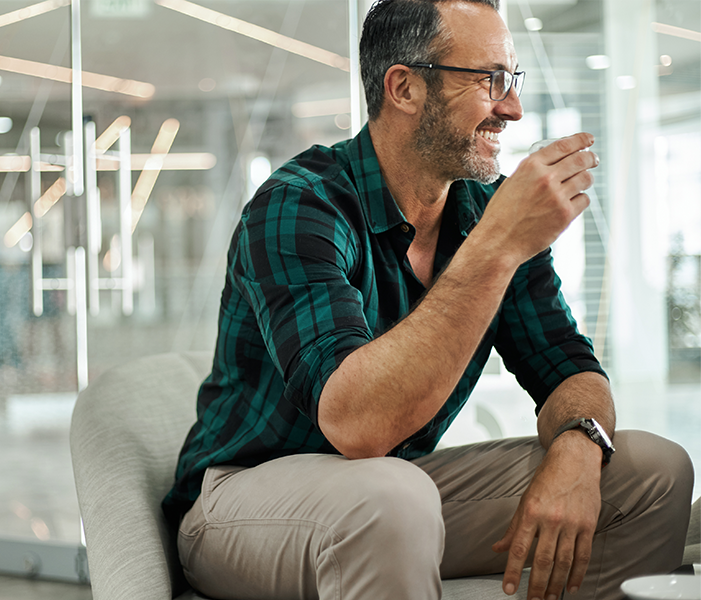 Man smiling while drinking espresso in an office breakroom