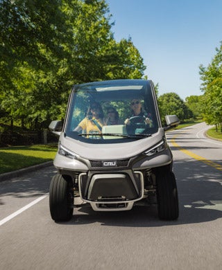 People drive Club Car Cru down street