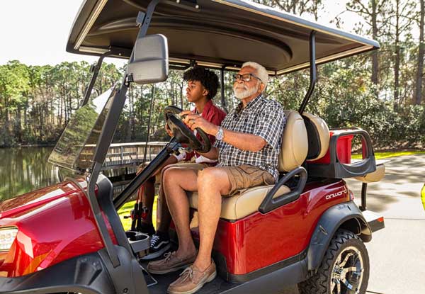 Red Onward lifted 4 passenger golf cart driving at river