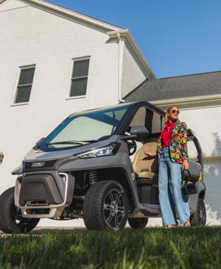 Woman stands next to Club Car Cru in driveway