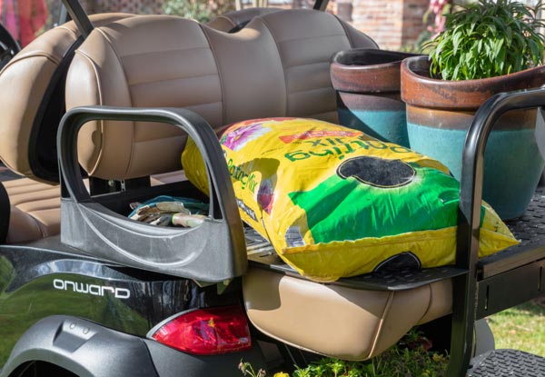 Potted plants and fertilizer sitting on back seats of a Club Car Onward
