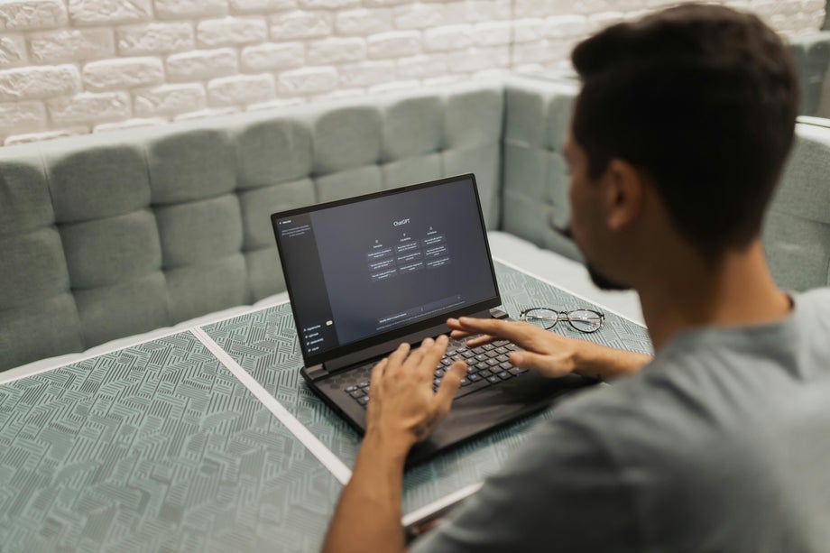 A person uses ChatGPT at a table on a laptop