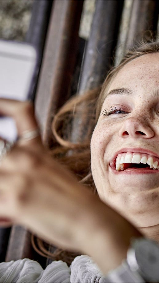 A girl looks happy as she checks something on her smart phone